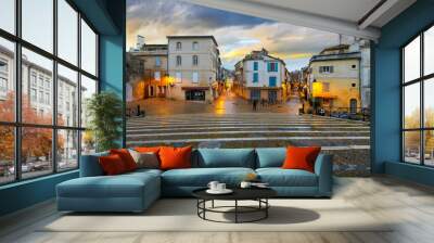 Illuminated shops and cafes after an evening rain seen from the steps of the ancient arena in the historic medieval old town of Arles, France, in the Provence region. Wall mural