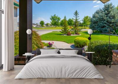 View from the front porch of a modern suburban home with a manicured front lawn in a nice community neighborhood across the street to a park on a sunny summer day. Wall mural