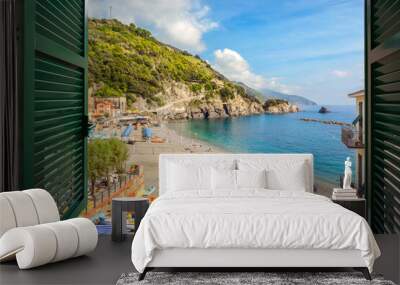 Window view of the sandy beach and clear blue water on the old side of the village of Monterosso Al Mare on the Ligurian coast of Cinque Terre, Italy. Wall mural