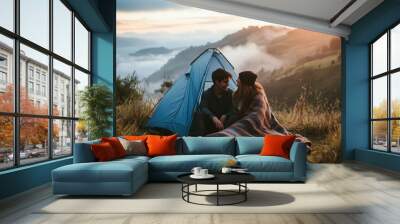 Couple relaxing by tent in grass. Wall mural