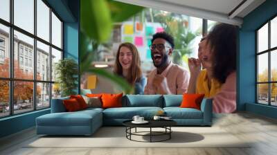 Diverse group of young professionals laughing during a creative meeting in a modern office space with sticky notes background Wall mural