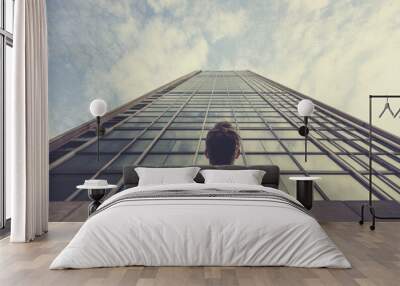 Man gazing up at a towering building, dwarfed by its imposing height. Wall mural