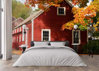 Orange autumn leaves frame a read house in a small New England town in fall Wall mural