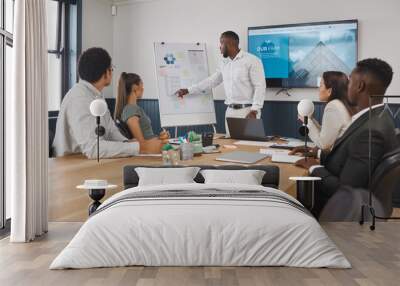 A group of young diverse corporate business people working as a team on a project in a boardroom. African American man speaker using a chart and graph to discuss statistics and planning a strategy Wall mural