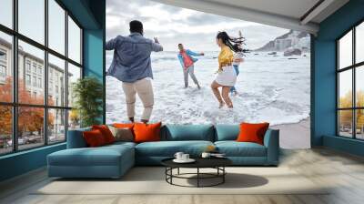 Friends at beach, water splash and ocean with travel and adventure, group of people have fun on holiday. Diversity, playful and nature, social get together and laugh, freedom outdoor in Los Angeles Wall mural