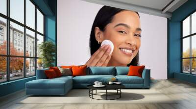 Happy woman, cotton pad and cleaning face in skincare for makeup removal against a grey studio background. Portrait of female person wiping product, cosmetics or remove with swab for facial treatment Wall mural