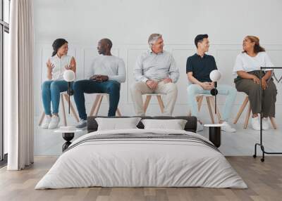 We can learn a lot by listening to each others stories. Shot of a diverse group of people talking to each other while sitting in line against a white background. Wall mural