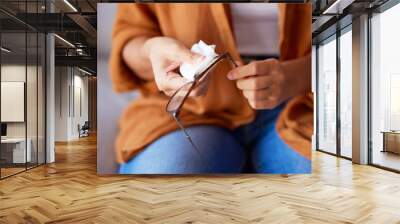 Woman cleaning glasses for dust, dirt and eye care protection with fabric tissue. Closeup female hands, microfiber cloth and spectacles, frames and eyewear for clear vision and optic lens maintenance Wall mural