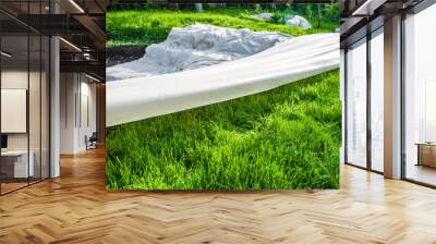 A canvas of white geotextile lies on the green grass outside Wall mural