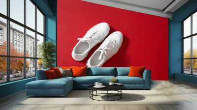 New white trendy sneakers for women on red wall background. Wall mural