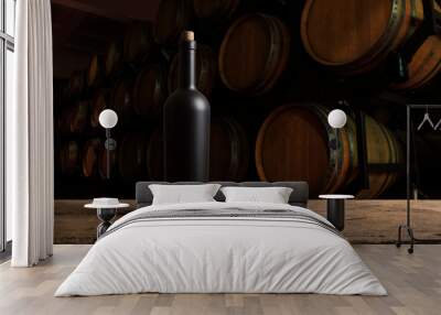 Expensive wine bottles collection and wooden barrel in the cellar, wine tasting and production concept Wall mural