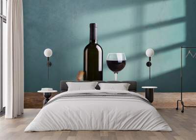 Pouring red wine into the glass against wooden background Wall mural