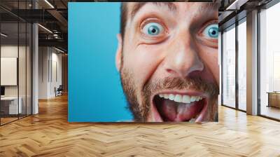 Close up Portrait of Excited Man with Wide Eyes and Open Mouth on Blue Background Wall mural