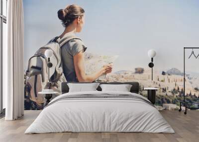 Back side of traveler girl searching right direction on map in Athens with Acropolis on background, traveling along Europe, freedom and active lifestyle concept Wall mural