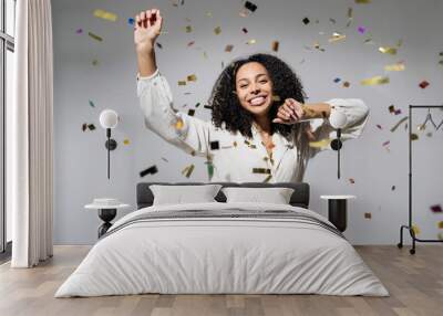 Beautiful young woman at celebration party with confetti falling everywhere on her. Birthday or New Year eve celebrating concept Wall mural