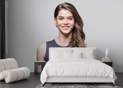 Beautiful young woman portrait. Smiling girl looking to camera. Isolated on gray background Wall mural