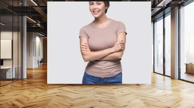 Beautiful young woman studio closeup portrait. Girl with crossed arms looking at camera isolated on gray background. Model with perfect clean skin. Beauty, makeup, healthy lifestyle, skin care concept Wall mural