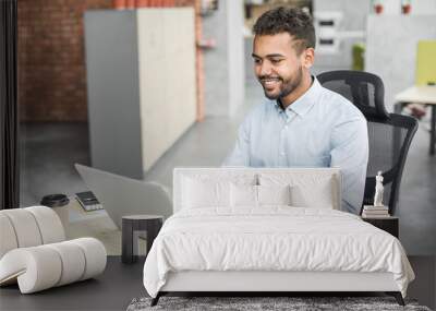 cheerful businessman working in office. young smiling professional man using laptop computer. intern Wall mural