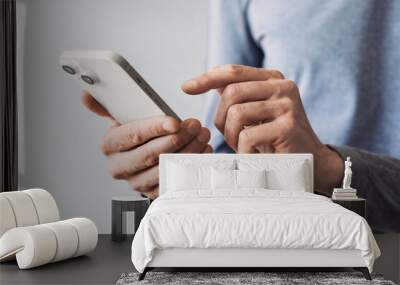 Closeup of adult male hand using mobile phone, Young man texting on smartphone over grey background. Wall mural