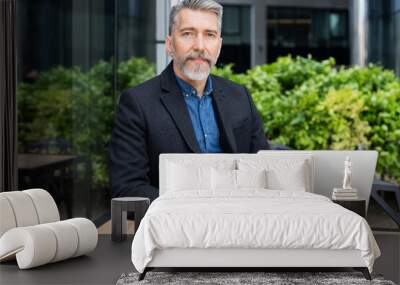 Handsome middle age man using laptop computer in a city. Mature man working outdoors. Modern lifestyle, active seniors, connection, technology, people, business concept Wall mural