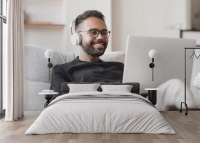 Handsome young man using laptop computer at home. Student men resting in his room. Home work or study, freelance, online learning and communication concept Wall mural