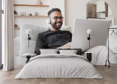 Handsome young man using laptop computer at home. Student men resting in his room. Home work or study, freelance and communication concept Wall mural