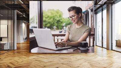 happy woman using laptop at cafe. young beautiful girl sitting in a coffee shop and working on compu Wall mural