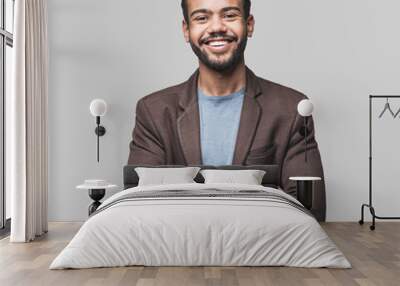 Portrait of handsome smiling young man with folded arms. Laughing joyful cheerful men with crossed hands studio shot. Isolated on gray background Wall mural