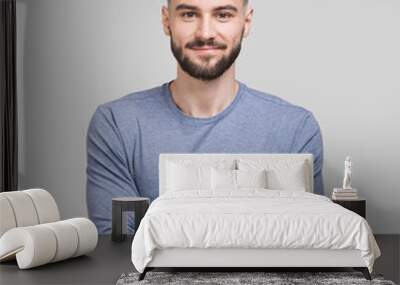 Portrait of handsome smiling young man with folded arms. Serious cheerful men with crossed hands studio shot. Isolated on gray background Wall mural