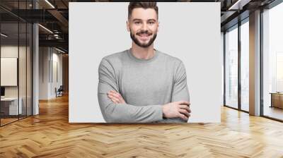 Portrait of handsome smiling young man with folded arms. Smiling joyful cheerful men with crossed hands isolated studio shot. Wall mural