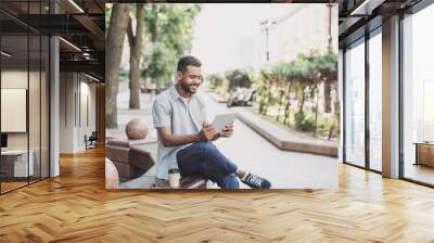 Smiling young man using digital tablet in a city, Handsome student men having coffee break, Modern lifestyle, connection, business, freelance work concept Wall mural