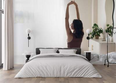 Woman stretching in bed after waking up, back view. Young woman in bed after sleeping, wake up happy, healthy lifestyle, mindfulness, wellbeing, enjoy life concepts Wall mural