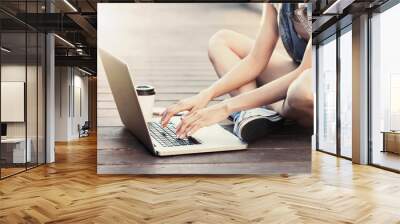 Young adult using laptop outdoors Wall mural