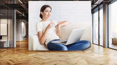 Young beautiful woman using a laptop computer at home Wall mural