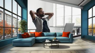 Young businessman relaxing at office workplace, Smiling man working on laptop computer in modern office, successful business, leadership, worker lifestyle concept Wall mural