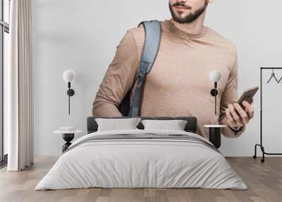 Young handsome man with backpack holding coffee cup isolated on gray background. Smiling student or businessman portrait. Studio shot of cheerful men going on travel  Wall mural