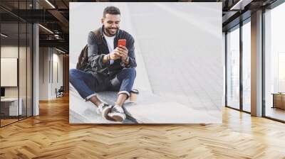 Young handsome men using smartphone in a city. Smiling student man texting on his mobile phone. Coffee break. Modern lifestyle, connection, business concept Wall mural