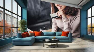 Young woman holding credit card and using laptop computer. Online shopping concept Wall mural