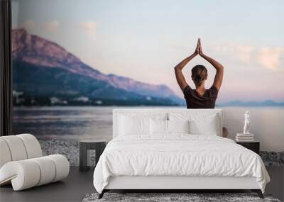 Young woman practicing yoga near the sea. Harmony and meditation concept. Healthy lifestyle Wall mural