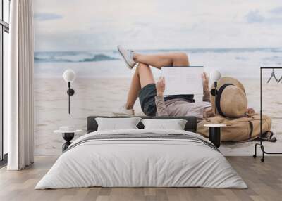 Young woman reading a book on the beach. Relaxation resting vacations concept Wall mural