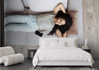 Young woman relaxing at home lying on sofa. African american girl resting in her room. Enjoy life, rest, relaxation, wellbeing, lifestyle, people, recreation concept Wall mural