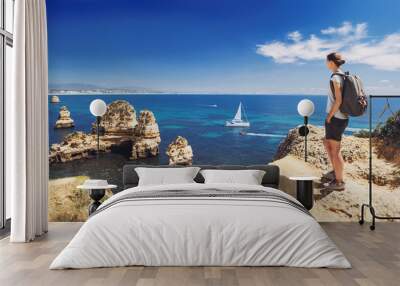 Young woman traveler looking at the sea in Lagos town, Algarve region, Portugal. Travel and active lifestyle concept Wall mural