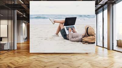 young woman using laptop computer on a beach. freelance work, online learning, distance work concept Wall mural