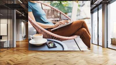 Young woman using laptop outdoor. Young beautiful girl sitting in a coffee shop terrace and working on computer Wall mural