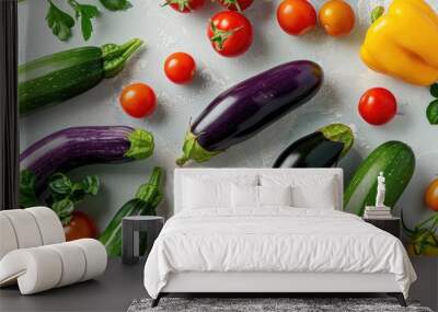 A collection of vibrant vegetables like eggplants, zucchini, and cherry tomatoes spread on a light background, leaving room for text Wall mural