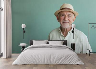 Elderly man in a relaxed pose, smiling, in front of a solid light green background with copy space Wall mural