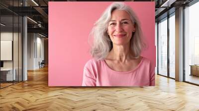 Half-body photo of a middle-aged woman, smiling confidently against a solid pink background, offering plenty of copy space Wall mural