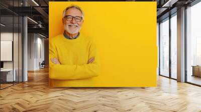 Half body shot of a cheerful older man, wearing glasses, standing against a solid yellow background with room for messaging Wall mural