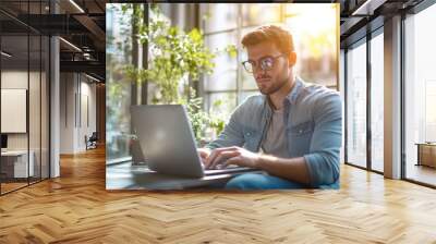 High-resolution brightly lit photorealistic candid photograph of a confident young marketer in casual attire, focused on his laptop in a sunlit office. The photograph is styled like a high-end Wall mural