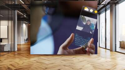 A man in the city, use the transparent phone with the latest technology for video calls with holography family on vacation. Concept: technology, future and futuristic technology, family	 Wall mural